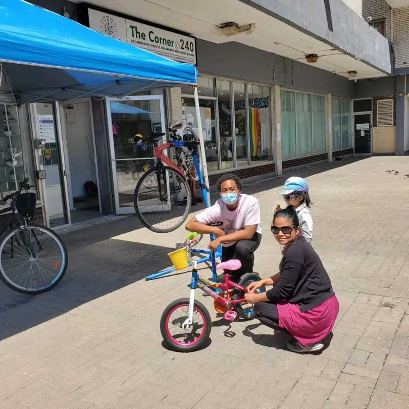 A girl with her mother getting her bike fixed by the corner staff